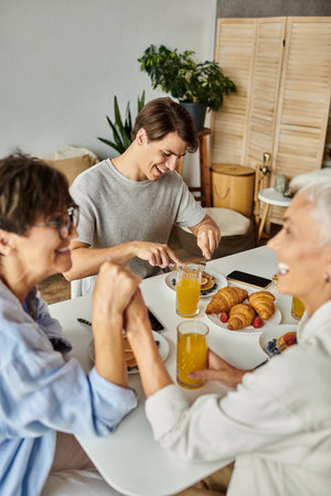 A joyful family enjoys breakfast together, sharing laughter and delicious food in a warm atmosphere.の写真素材