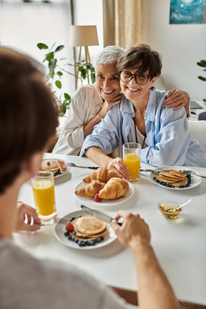A joyful LGBTQ family shares a delightful breakfast filled with warmth and laughter.の写真素材