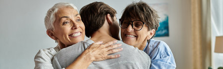 A warm moment shared as lesbian parents embrace their adult son, celebrating love and connection.の写真素材