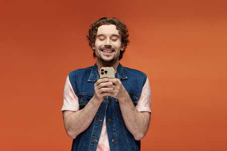 A cheerful man captivates with his smile while using a smartphone.