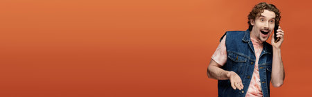 A joyful man engages in a lively phone conversation, showcasing vibrant emotions.の写真素材