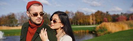 Under the warm autumn sun, a couple shares a loving moment near a tranquil lake.