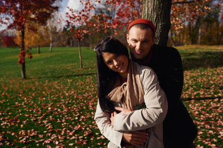 A loving couple enjoys a tender moment outdoors amid colorful autumn leaves.の写真素材
