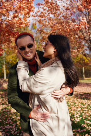 A couple shares a loving moment while surrounded by vibrant autumn foliage, enjoying the season.