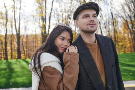 A couple sharing a tender moment amidst vibrant autumn foliage, showcasing their affection.