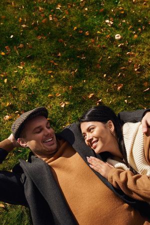 A couple relaxes together on a grassy patch, enjoying each others warmth amidst autumns beauty.の写真素材