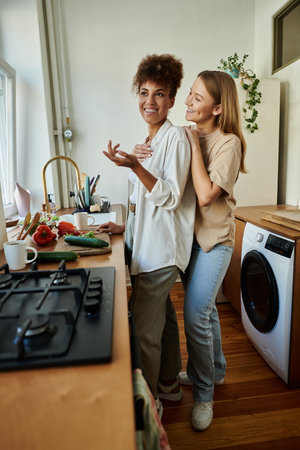 Two partners share laughter while preparing a meal together in their vibrant kitchen.の写真素材