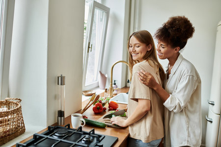 Two partners joyfully prepare a meal side by side in their cozy kitchen.の写真素材