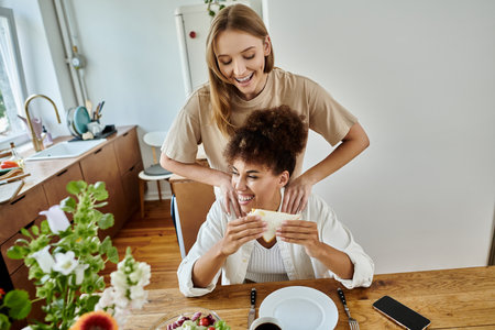 Two partners share a playful moment while enjoying a meal at home.の写真素材