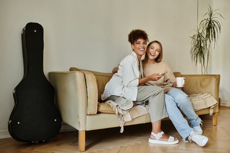 A happy couple shares laughter and warmth while sipping tea on a comfortable couch.