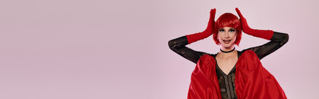 An attractive drag queen showcases a stunning red outfit and playful pose.の写真素材