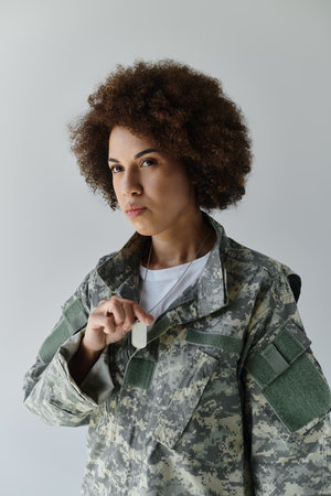 A young African American woman in a camouflage uniform showcases her determination with confidence.の写真素材