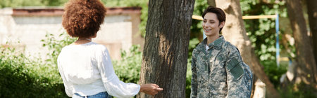 A young soldier in a camouflage uniform is warmly embraced by her wife in a lush garden.