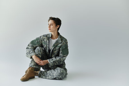 woman prepares for military service in a studio with a grey backdrop.の写真素材