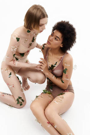 Two women share an intimate connection adorned with floral accents.の写真素材