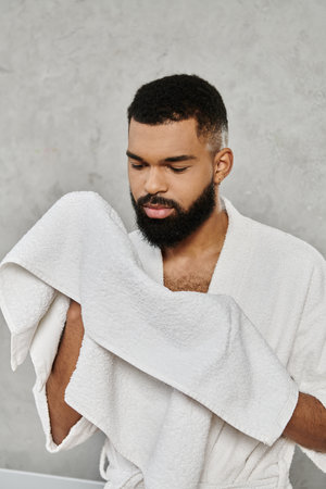 A man enjoying a quiet moment, holding towel, reflecting peacefully at home.の写真素材