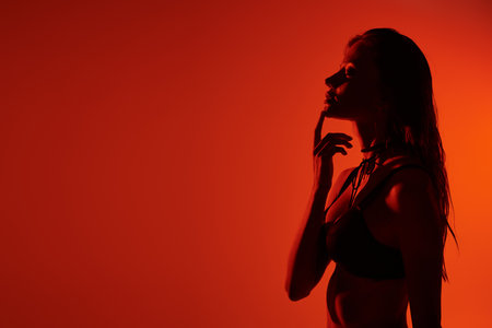 A young woman poised gracefully in alluring lingerie, bathed in warm light.の写真素材