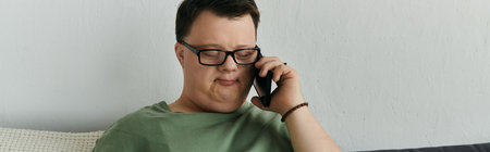 A man with Down syndrome chats on the phone, smiling in his comfortable living space.