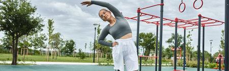 A young woman in sportswear stretches happily outdoors, enjoying fitness and movement in a vibrant...
