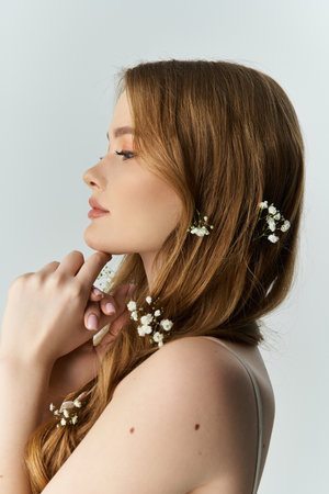 A young woman poses gracefully with delicate flowers in her hair, exuding beauty.の写真素材