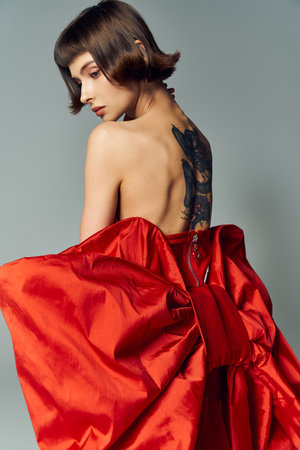 A stylish young woman poses gracefully in a bold red gown.の写真素材
