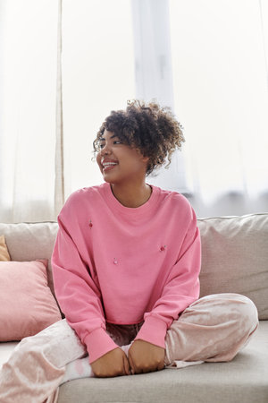 Smiling woman dressed casually enjoys a peaceful day in her sunny home.の写真素材