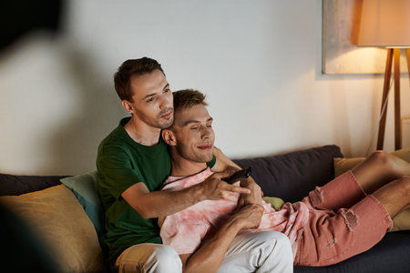 Two men share joy and laughter while cuddling on the couch.の写真素材