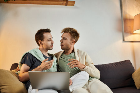 Two men share a warm moment while chatting on the couch.の写真素材