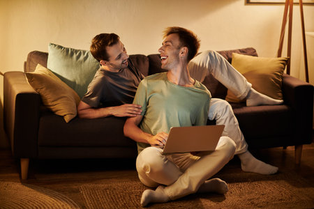 Two men share laughter and connection while relaxing on the couch.の写真素材