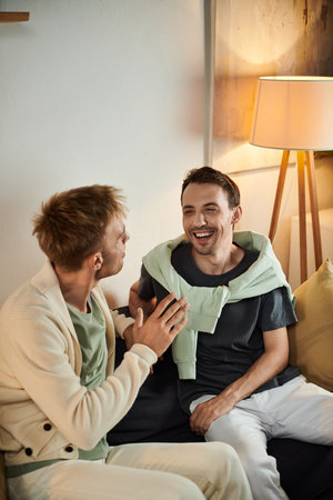 Two men share laughter and warmth while lounging together at home.