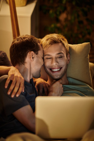 Two men share tender moments while enjoying time together on a couch.の写真素材
