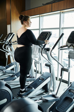 A plus-size woman confidently works out at the gym, embracing body positivity in stylish active...