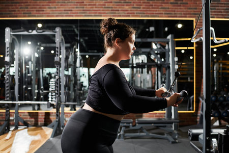 A plus-size woman confidently works out, showcasing strength and positivity in her fitness journey.