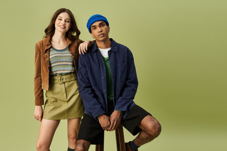A trendy couple enjoys a playful moment, dressed in striking autumn outfits filled with color.