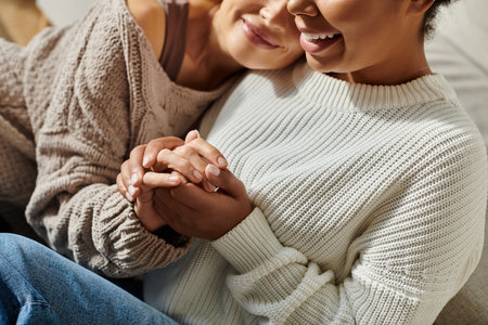 Two women smile gently while holding hands, enjoying each others warmth and connection.の写真素材