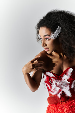 A young woman exudes confidence in a vibrant red outfit adorned with feathers, showcasing elegance.の写真素材