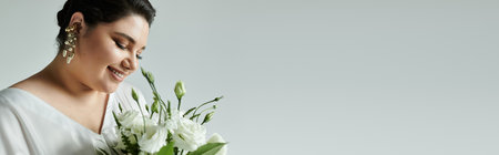 A joyful plus size bride admires her bouquet while dressed in a stunning white wedding gown.の写真素材