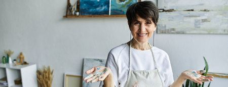A mature woman joyfully expresses her creativity in her art studio.
