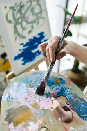 A mature woman blends colors on her palette, immersed in her artistic process.の写真素材