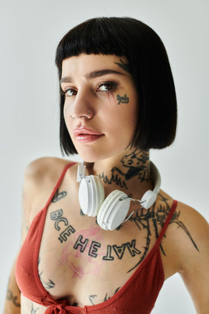 A stylish young woman showcases her tattoos while wearing headphones.
