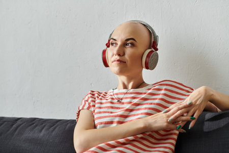 A young woman with alopecia listens to music, immersed in her thoughts, in a tranquil space.