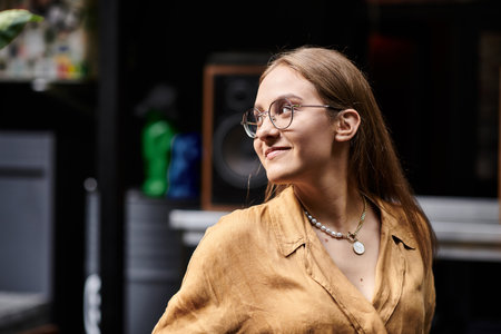 A young woman smiles as she looking away in a lively cafe, embracing her daily activities with joy.の写真素材