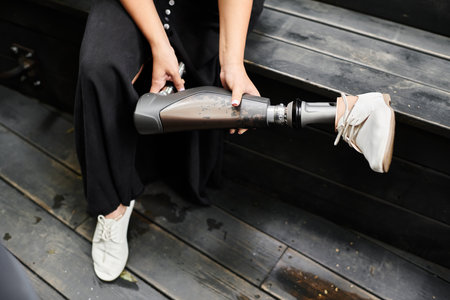 A young woman sits in a cozy cafe, adjusting her artificial limb