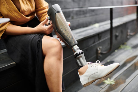 In a cozy cafe, a young woman with an artificial limb relaxes on bench, embracing her unique lifestyle.の写真素材