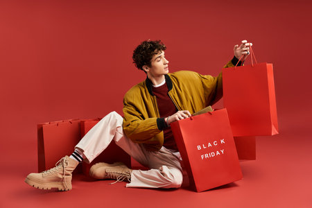 A fashionable young man holds vibrant shopping bags, celebrating Black Friday in a lively studio...