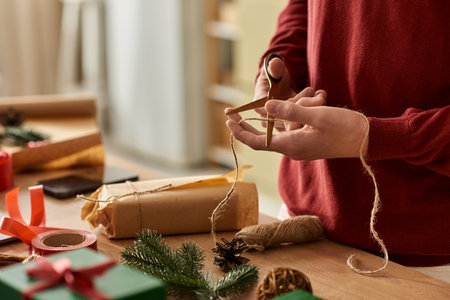 A young man wraps Christmas gifts with thoughtful precision and joyful spirit at home.の写真素材