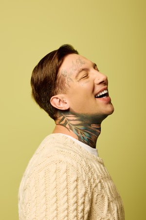 The young man shows off his tattoos while smiling joyfully in front of a bright backdrop.の写真素材