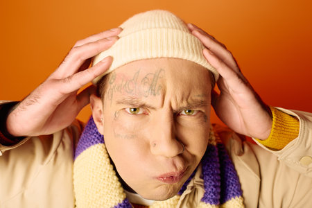 A young man with tattoos shows frustration while clutching his head, surrounded by bright colors.の写真素材
