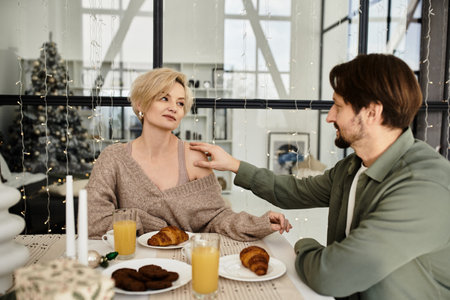 A couple shares a tender moment at their dining table filled with breakfast treats.の写真素材