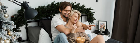 A warm moment unfolds as a couple shares laughter together while enjoying snacks at home.の写真素材